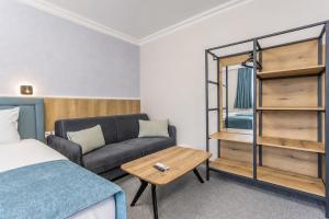 a bedroom with a bed and a couch and a table at Хотел EFES in Burgas