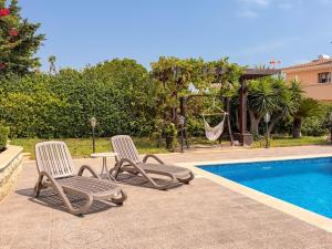 two chairs and a table and a hammock by a pool at Luxury Villa Aurelia in Peyia
