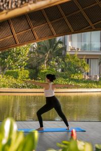 a woman doing a yoga pose in front of a pond at The Ocean Resort by Fusion Quy Nhon in Quy Nhon