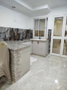 a kitchen with a counter and a sink and windows at Lemjid maison in Kelibia