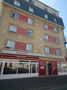 a large brick building with red accents on a street at The Originals City, Hôtel Le Savoy, Caen in Caen