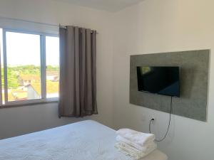 a bedroom with a bed with a tv and a window at Fortal Flat in Fortaleza