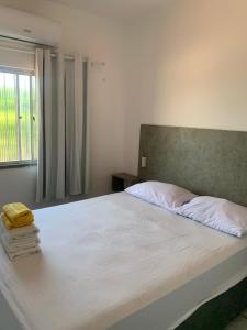 a bedroom with a large white bed with a window at Fortal Flat in Fortaleza