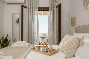 a white bedroom with a tray of food on a bed at Villa Irina in Agios Prokopios