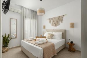 a white bedroom with a bed and a mirror at Villa Irina in Agios Prokopios