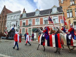 a group of men in uniform are riding horses with an american flag at Suite Stays Bruges - Pandreitje 6 in Bruges