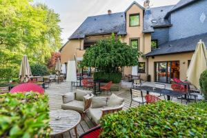 an outdoor patio with tables and chairs and umbrellas at Hôtel Antares & Spa in Honfleur