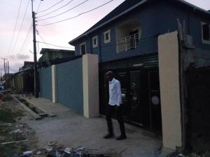 a man standing in front of a blue building at ifetomitola in Iseri-Osun