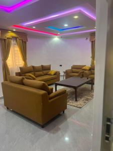 a living room with couches and a table and purple lights at ifetomitola in Iseri-Osun