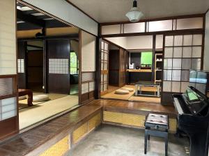 a living room with a piano in a room with windows at 川辺の時-Kawabe 川-山-BBQ in Hanno