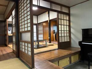 an asian room with a door and a piano at 川辺の時-Kawabe 川-山-BBQ in Hanno