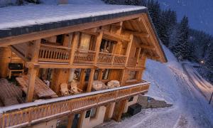a large wooden building with snow on the ground at Chalet Serbijanka Alpine Retreat with Hammam Sauna and Jacuzzi for 14 Gueststs in Manigod
