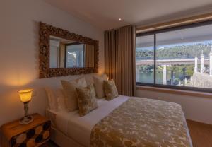 ein Schlafzimmer mit einem Bett, einem Spiegel und einem Fenster in der Unterkunft Estrelas do Douro in Gondomar