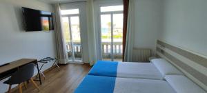 a bedroom with a bed and a desk and a television at Hotel Miramar Playa America Nigran in Nigrán