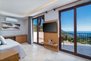 a bedroom with a bed and a tv and a balcony at Turquoise Retreat Spa & Wellness in Kaş