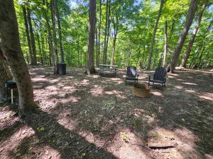 two chairs and a barrel in a forest with trees at The Hocking Hills Store Campsite #2 in Logan