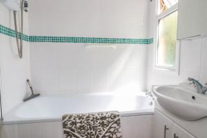 a white bathroom with a tub and a sink at Coombe Lodge No 9 in Bude +9 photos