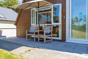 a table and two chairs with an umbrella on a house at Coombe Lodge No 9 in Bude