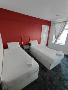 two beds in a hotel room with red walls at Harbour Stays in Skegness