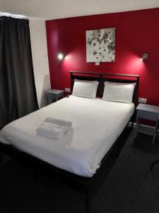 a bedroom with a large white bed with a red wall at Harbour Stays in Skegness +26 photos