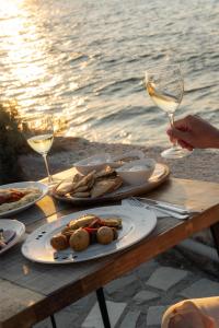 a table with plates of food and glasses of wine at Pounda Resort Paros, a member of Radisson Individuals in Pounda