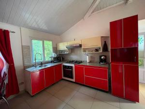 a red kitchen with red cabinets and a sink at GranjaKatKery in Cerro Azul