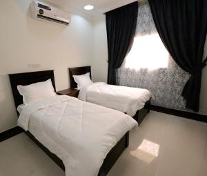 two beds in a room with a window at شقق روز وود للشقق المخدومة in Taif