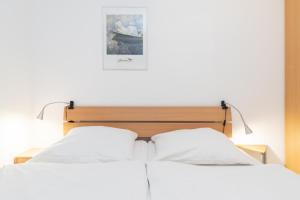 a bedroom with two white beds and a picture on the wall at Haus Roland, Wohnung 16 in Zinnowitz