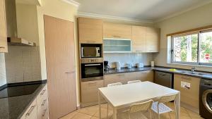 a kitchen with a white table and a microwave at Santa Maria N - Shared Pool - 8 Guests - Albufeira in Albufeira