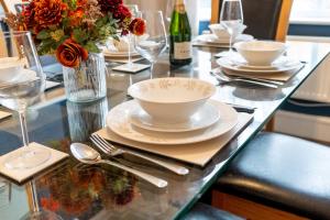 a table with plates and glasses and a vase of flowers at Family Friendly I Pets Welcome I Short Walk to Railway Station I 10min Drive to Safari Park in Kidderminster