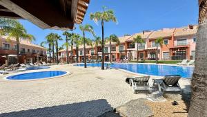 a pool at a resort with chairs and palm trees at Santa Maria N - Shared Pool - 8 Guests - Albufeira in Albufeira