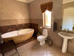 a bathroom with a tub and a toilet and a sink at Zomoya Game Farm in Vaalwater