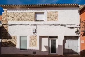 a white facade of a building with windows at La cochera by Óscar Fuentes in Alcocer de Planes