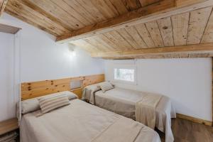 two beds in a room with wooden ceilings at La cochera by Óscar Fuentes in Alcocer de Planes