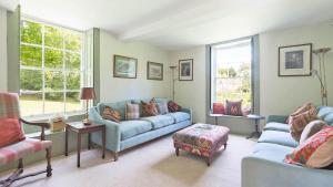 a living room with two blue couches and a window at Almsbury Farmhouse in Winchcombe