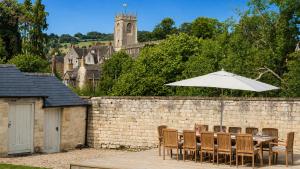 a table with an umbrella next to a brick wall at Almsbury Farmhouse in Winchcombe