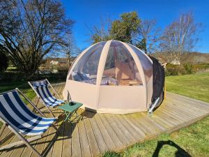 two chairs and a tent on a deck at Bulle insolite Wigwam in Aulnay-sur-Iton
