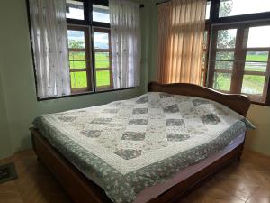 a bedroom with a quilt on a bed with windows at Darins House in Nan