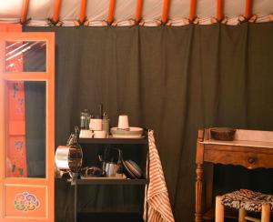 a kitchen with green curtains and a shelf with dishes at Yourte vue exceptionnelle in Teillet