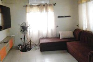 a living room with a couch and a fan at Royal Garden Residence in Apégame