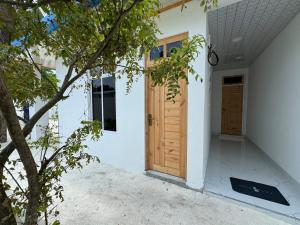 a house with white walls and wooden doors at Reethi Stay Omadhoo in Reethi Rah