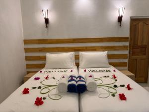 a bedroom with two beds with flip flops and flowers at Reethi Stay Omadhoo in Reethi Rah