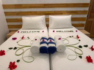 two beds with towels and flowers on the bed at Reethi Stay Omadhoo in Reethi Rah