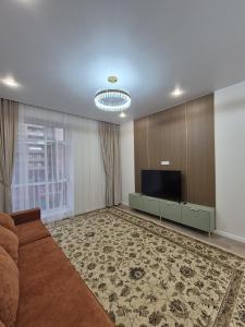 a living room with a couch and a flat screen tv at ЖК Geneva in Astana