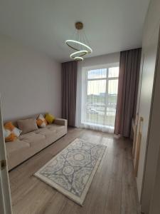a living room with a couch and a large window at ЖК Geneva in Astana
