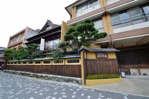 un edificio con una puerta de madera y una valla en Hamachiyokan, en Ise