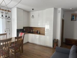 a kitchen with white cabinets and a table and chairs at Luxoro Park Apartament Nero in Ustka