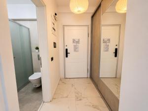 a bathroom with a toilet and two white doors at Studio Sea On Beach in Mamaia +7 photos