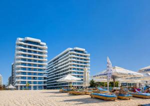 a beach with chairs and umbrellas and two tall buildings at Studio Sea On Beach in Mamaia