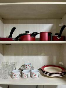 a shelf with pots and pans and cups and plates at WestFlat - BarretoStays 01 in Mossoró +9 photos